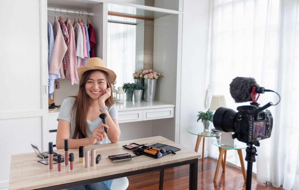 Blogger recording vlog video with makeup and cosmetics