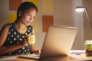 Young woman working on her laptop in her office at night