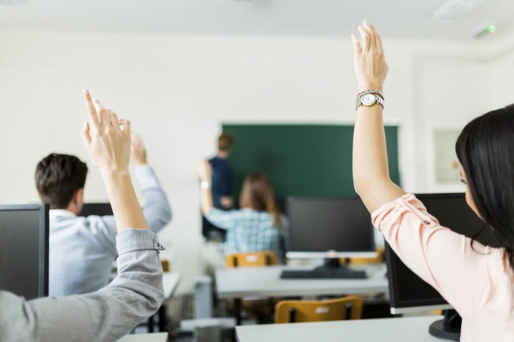 Young students raising hands in a classroom