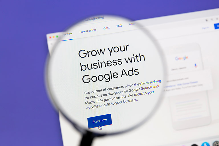 Google Ads website under a magnifying glass. Google Ads is an online advertising platform developed by Google